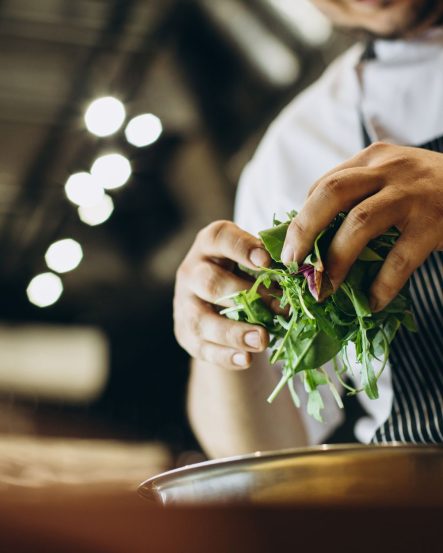 Chef at the kitchen preparing salad
